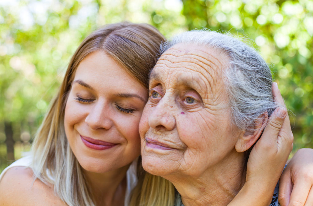 Woman hugs senior with dementia