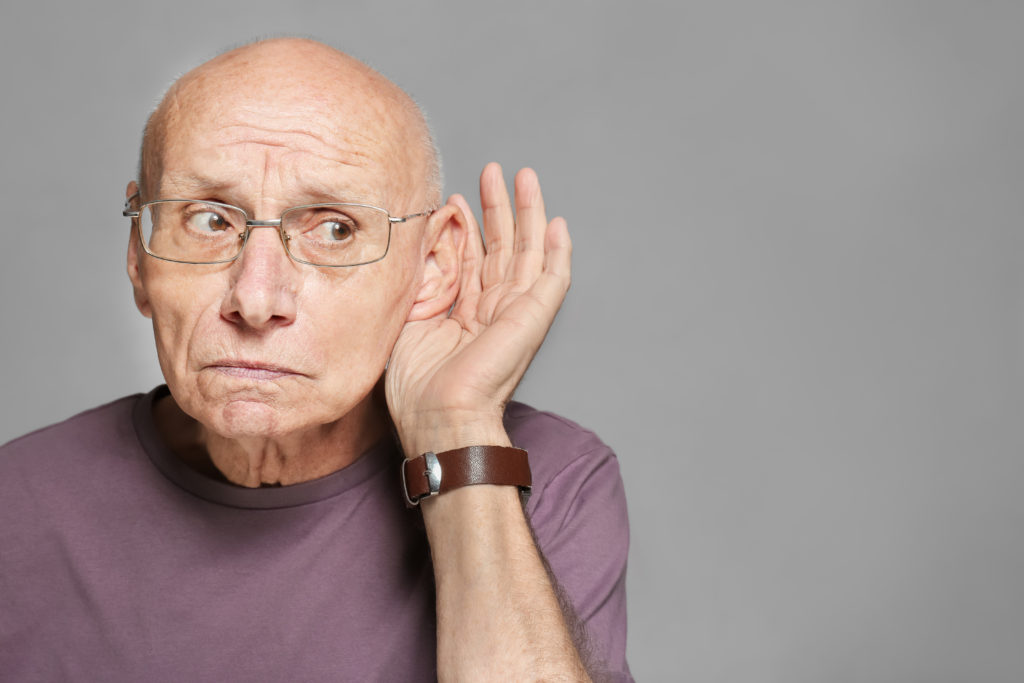 Elderly man with hearing problem on grey background