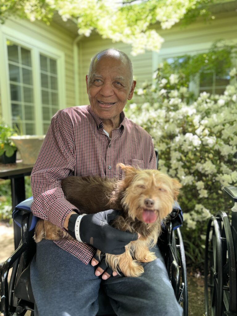 senior in wheelchair holding small dog 